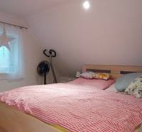 Útulný domček s dušou a moderným komfortom – Divín - Spálňa v podkroví rodinného domu s posteľou, televízorom a podlahou s dreveným dekorom.