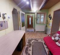 Útulný rodinný dom v Hronskom Beňadiku s veľkým pozemkom - Interiér rodinného domu s podlahou s dreveným dekorom, pohodlnou sedačkou a dekoráciami.