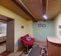 Útulný rodinný dom v Hronskom Beňadiku s veľkým pozemkom - Izba v rodinnom dome s podlahou s dreveným dekorom, sedačkou a malým stolom.