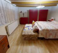 Útulný rodinný dom v Hronskom Beňadiku s veľkým pozemkom - Spálňa v rodinnom dome s posteľou, šatníkovými skriňami a podlahou s dreveným dekorom.