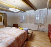 Útulný rodinný dom v Hronskom Beňadiku s veľkým pozemkom - Izba v rodinnom dome s podlahou s dreveným dekorom, posteľou a červenou skriňou.