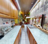 Útulný rodinný dom v Hronskom Beňadiku s veľkým pozemkom - Kuchyňa v rodinnom dome so skrinkami, spotrebičmi a výhľadom do záhrady cez veľké okno.