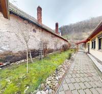 Útulný rodinný dom v Hronskom Beňadiku s veľkým pozemkom - Rodinný dom na Hlavnej ulici v Hronskom Beňadiku s dláždeným chodníkom vedľa trávnika.