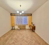 Predaj pôvodného 3+1 bytu v žiadanej lokalite v Čadci (MO) - Izba v 3-izbovom byte s podlahou s dreveným dekorom, záclonami a komodou.