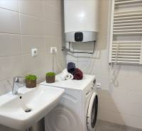 2-izbový byt novostavba s podzemným parkovaním- bez rezervačnej zálohy - Kúpeľňa v 2-izbovom byte s práčkou, umývadlom a bojlerom na bielych obkladoch.