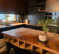 2-izbový byt v Pezinku s vlastným parkovaním - REZERVOVANÉ - Kuchyňa v 2-izbovom byte s podlahou s dreveným dekorom a čiernou kuchynskou linkou.