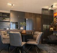 2-izbový byt v Pezinku s vlastným parkovaním - REZERVOVANÉ - Kuchyňa v 2-izbovom byte s tmavými skrinkami a dekoratívnymi plagátmi na stene.