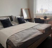 2-izbový byt v Pezinku s vlastným parkovaním - REZERVOVANÉ - Spálňa v 2-izbovom byte s posteľou, písacím stolom a podlahou s dreveným dekorom.