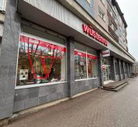 Exkluzívne - Obchodný priestor na prenájom v centre mesta Poprad - Obchodné priestory v Poprade s výrazným červeným logom na budove.