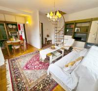 Predaj rekreačná chata s pozemkom, garážou a saunou Modra, Harmónia - Interiér chaty so špirálovým schodiskom, televíziou a stolom na podlahe s dreveným dekorom.