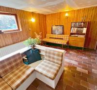 Predaj rekreačná chata s pozemkom, garážou a saunou Modra, Harmónia - Interiér chaty s obývačkou, rustikálnym nábytkom a tehlovou podlahou.