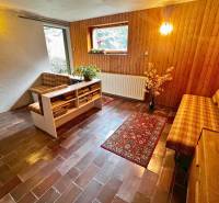 Predaj rekreačná chata s pozemkom, garážou a saunou Modra, Harmónia - Obývacia časť v chate s tehlovou dlažbou a dreveným dekorom na stenách.