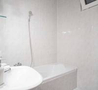 Na prenájom veľký 4-izbový byt s balkónom, garážou a záhradou, Kolta – - Kúpeľňa s vaňou a práčkou v 4-izbovom byte. Steny pokryté svetlými obkladačkami.