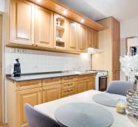 Na prenájom veľký 4-izbový byt s balkónom, garážou a záhradou, Kolta – - Kuchyňa v 4-izbovom byte s drevenými skrinkami, kvetmi a jedálenským stolom.