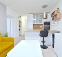ŠTÚROVA, 3-i byt, 75 m2 – komplet rekonštrukcia, vlastné parkovanie - Kuchyňa a obývačka v 3-izbovom byte s bielym nábytkom a žltou sedačkou.