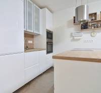 ŠTÚROVA, 3-i byt, 75 m2 – komplet rekonštrukcia, vlastné parkovanie - Kuchyňa v 3-izbovom byte s bielymi skrinkami a dreveným dekorom pracovnej dosky.