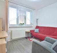 ŠTÚROVA, 3-i byt, 75 m2 – komplet rekonštrukcia, vlastné parkovanie - Izba v 3-izbovom byte s červenou sedačkou, kancelárskym stolom a podlahou s dreveným dekorom.