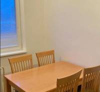 Prenájom 3 izbový byt, ulica Jána Poničana, BA IV. Devínska Nová Ves - Jedálenský stôl so štyrmi stoličkami v 3-izbovom byte, podlaha s dreveným dekorom.