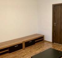 Prenájom 3 izbový byt, ulica Jána Poničana, BA IV. Devínska Nová Ves - Obývacia izba s podlahou s dreveným dekorom v 3-izbovom byte, svetlé steny, drevený nábytok.