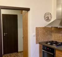 Prenájom 3 izbový byt, ulica Jána Poničana, BA IV. Devínska Nová Ves - Kuchyňa v 3-izbovom byte s plynovým sporákom, mozaikovým obkladom a podlahou s dreveným dekorom.