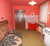  Na predaj 3 izbový dom v Kravanoch nad Dunajom s garážou . - Kuchyňa v rodinnom dome s červenými stenami, starším nábytkom a zeleným kobercom.