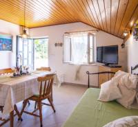 Na predaj krásny priestranný dom / 101 m²/ výhľadom na more  Čiovo - Rekreačný apartmán s jedálenským kútom, televízorom, otvoreným oknom a dreveným stropom.