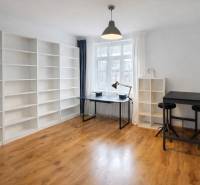 PRENÁJOM 2 izb byt Bratislava-Nové mesto Pri starej prachárni - Priestranná izba s regálmi, stolom a podlahou s dreveným dekorom v 2-izbovom byte.