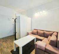 Prenájom, Garsónka, M.R.Štefánika, Centrum, Žilina - Garsónka s rohovou sedačkou, bielym stolíkom a podlahou s dreveným dekorom.