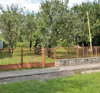 Pozemok v Lastomíre: veľkorysý priestor, pre široké možnosti, 1996 m2 - Dom a brána obklopené stromami na pozemkoch pre bývanie v Lastomíre.