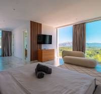 NA PREDAJ Luxusná vila  /360 m²/ s infinity bazénom, mesto Korčula - Svetlá spálňa vo Vile s výhľadom cez veľké okná, podlaha s dreveným dekorom.