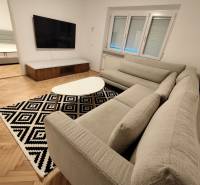 Na prenájom 2-izbový byt  Nové Zámky - Obývacia izba v 2-izbovom byte s veľkou TV a podlahou s dreveným dekorom.