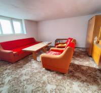 Rodinný dom v obci Borskom Mikuláš. - Obývačka v rodinnom dome s oranžovým gaučom, dreveným stolíkom a vitrínou.