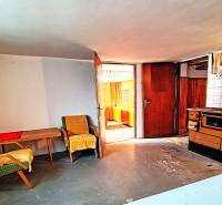 Rodinný dom v obci Borskom Mikuláš. - Izba v rodinnom dome s kreslami, stolom a starým sporákom.