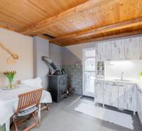 Záhradná chatka Handlová - Kuchyňa v chate s dreveným stropom, pecou a bielym nábytkom.