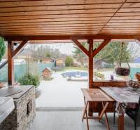 Záhradná chatka Handlová - Drevený prístrešok pri chate v Handlovej, s výhľadom na zasneženú záhradu a ploty.