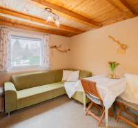 Záhradná chatka Handlová - Interiér chaty s rohovej sedačkou, stolom a dreveným stropom.