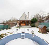 Záhradná chatka Handlová - Zasnežená záhrada s chatou v Handlovej a prázdnym bazénom v popredí.