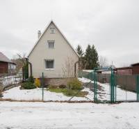 Záhradná chatka Handlová - Chata v Handlovej s trochou snehu na dvore, obklopená zeleňou a plotom.