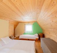 Záhradná chatka Handlová - Priestor v Chate s dreveným obložením, posteľami a podlahou s dreveným dekorom.