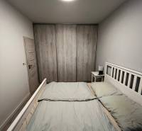 Predáme 2 izb byt v novostavbe v Senci  - Svetlá spálňa v 2-izbovom byte s priestrannou posteľou a skriňou s dreveným dekorom.