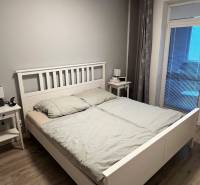 Predáme 2 izb byt v novostavbe v Senci  - Spálňa s podlahou s dreveným dekorom a jednoduchou posteľou v 2-izbovom byte.