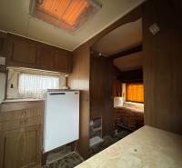 Predám pozemok v obci Dubník okr. Nové Zámky - Interiér s podlahou s dreveným dekorom, kuchynskou linkou a posteľou v Pozemky - bývanie.