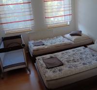 Viacgeneračný rodinný dom / investičná nehnuteľnosť – Dolná časť Zobor - Detská postieľka a dve postele v spálni s podlahou s dreveným dekorom.