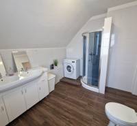 Viacgeneračný rodinný dom / investičná nehnuteľnosť – Dolná časť Zobor - Kúpeľňa v rodinnom dome s umývadlom, sprchovým kútom a podlahou s dreveným dekorom.