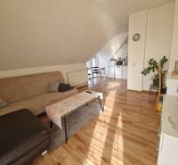 Viacgeneračný rodinný dom / investičná nehnuteľnosť – Dolná časť Zobor - Podkrovná obývacia izba v rodinnom dome s pohovkou, jedálenským stolom a podlahou s dreveným dekorom.