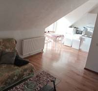 Viacgeneračný rodinný dom / investičná nehnuteľnosť – Dolná časť Zobor - Podkrovný priestor v rodinnom dome s kuchyňou, kvetinovou pohovkou a podlahou s dreveným dekorom.