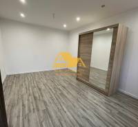 Prenajmem prerobený 1 izbový byt v Nových Zámkoch - Interiér 1-izbového bytu s podlahou s dreveným dekorom a vstavanou skriňou.