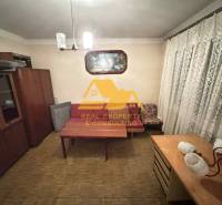 Predám rodinný dom s garážou v obci Dvory nad Žitavou - Izba v rodinnom dome s nábytkom, závesmi a podlahou s dreveným dekorom.