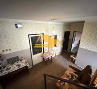 Predám rodinný dom s garážou v obci Dvory nad Žitavou - Interiér rodinného domu so vzorovanou tapetou, nábytkom a kvetinovou dekoráciou.