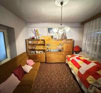 Predám rodinný dom s garážou v obci Dvory nad Žitavou - Obývacia izba v rodinnom dome s kobercom, pohovkou a skriňou s porcelánom.